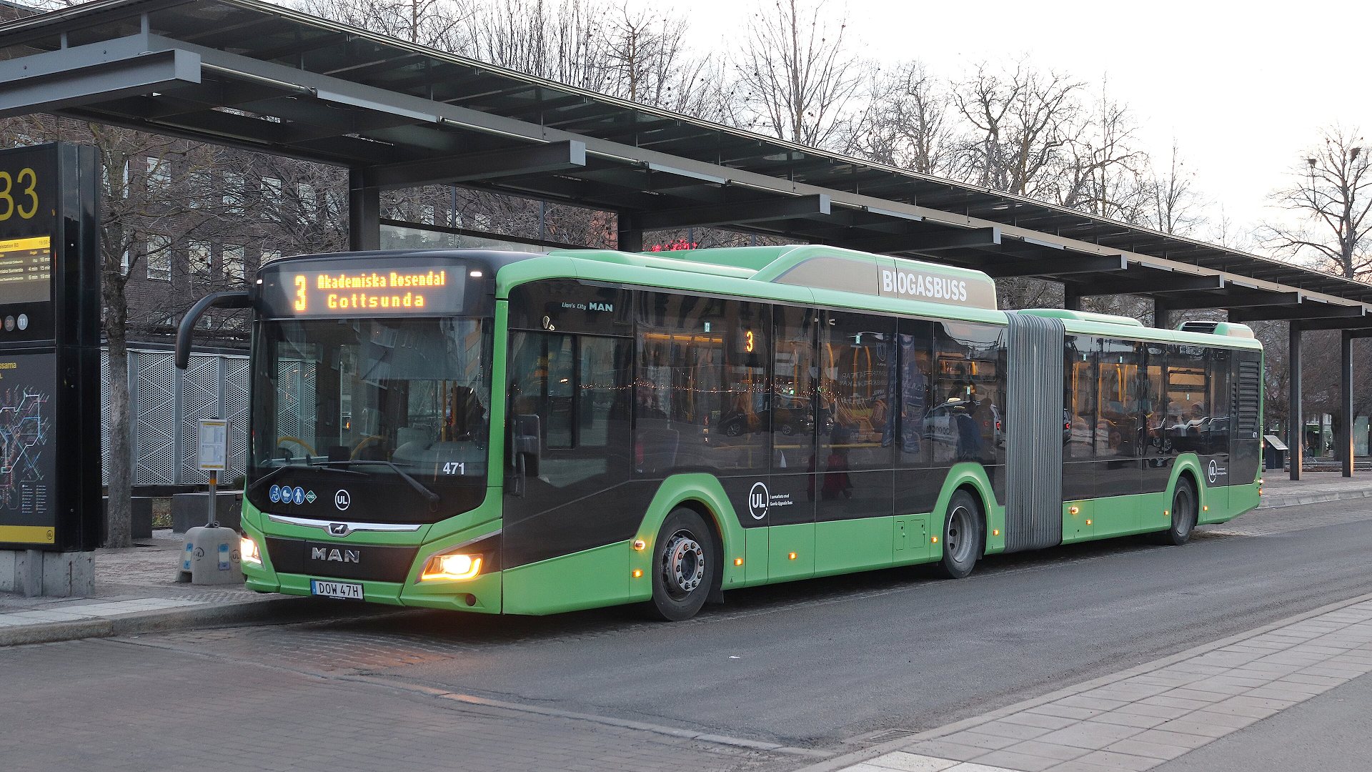 En grön buss står stilla på busstation.
