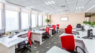 Kontor med vita arbetsbord och klarröda stolar.