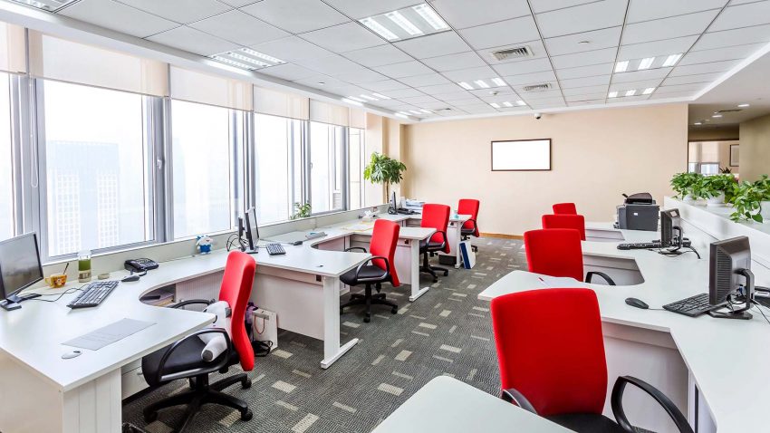 Kontor med vita arbetsbord och klarröda stolar.