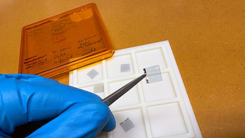 Pincett håller i en tunn genomskinlig fyrkant med metallkant.