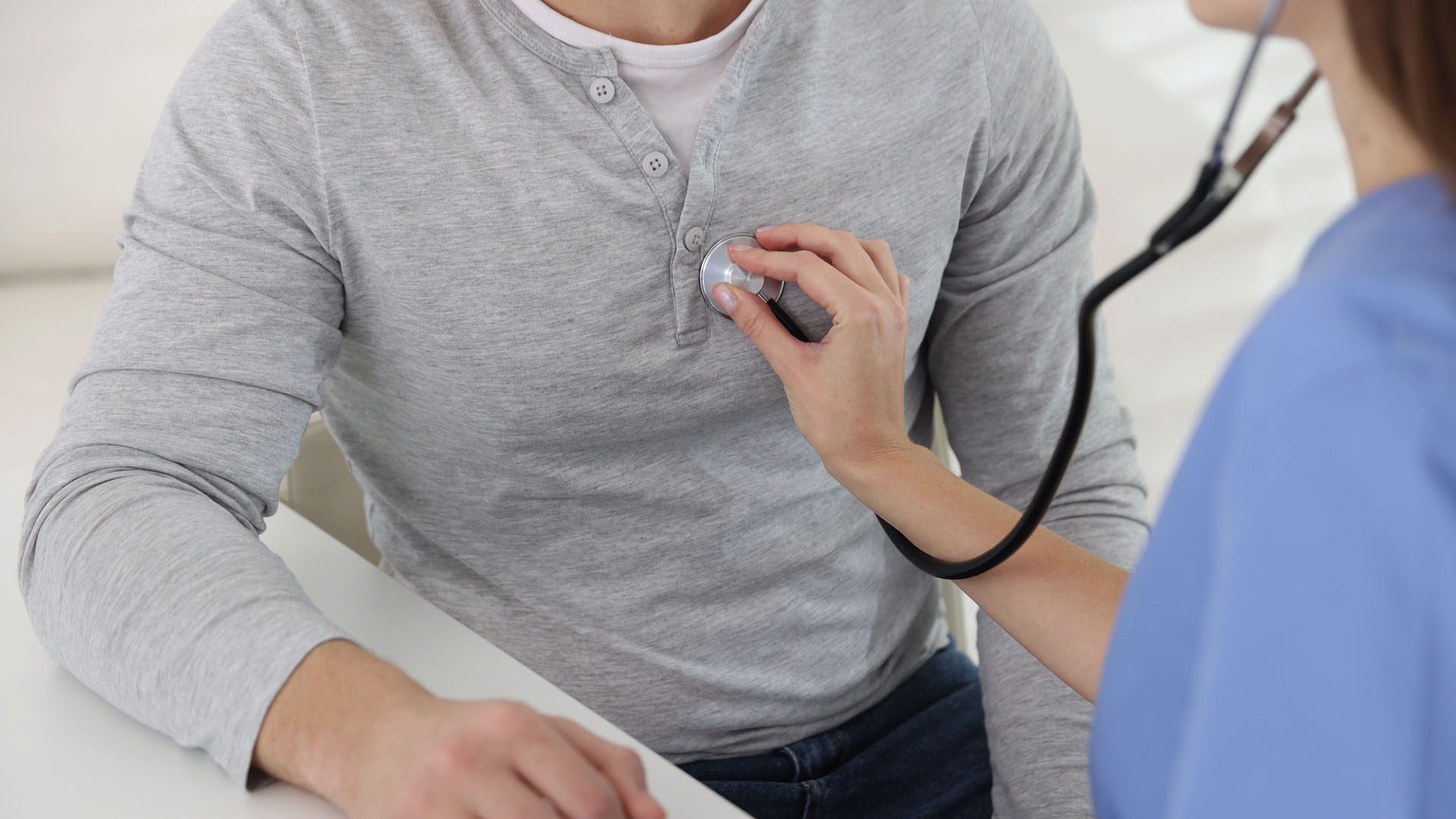 Läkare lyssnar på en mans hjärta med stetoskop.