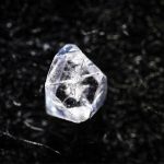 En diamantliknande sten som ligger på ett svart underlag.