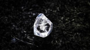 En diamantliknande sten som ligger på ett svart underlag.