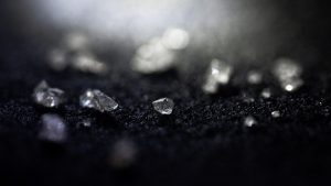 Stenar som ser ut som diamanter, mot svart underlag.
