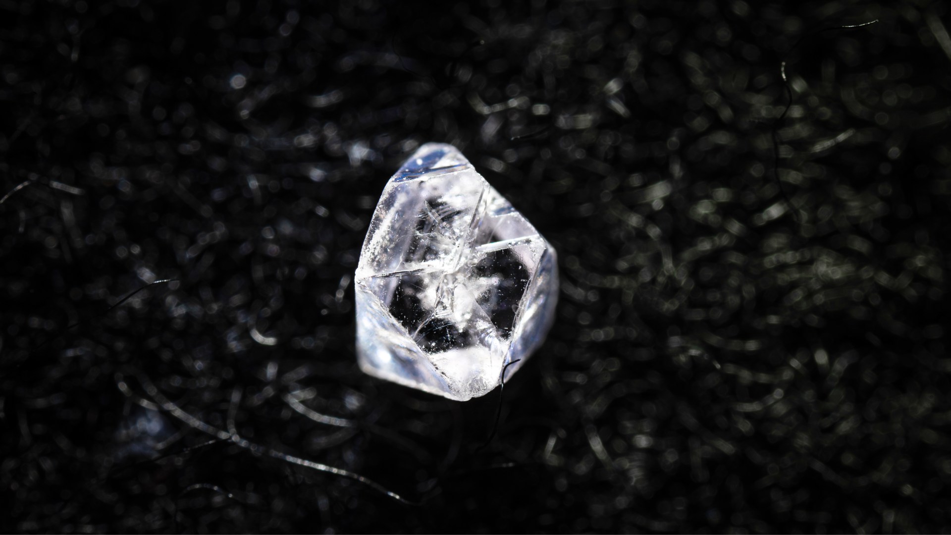 En diamantliknande sten som ligger på ett svart underlag.