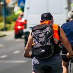 Människor cyklar på rad i stadsmiljö, sommartid.