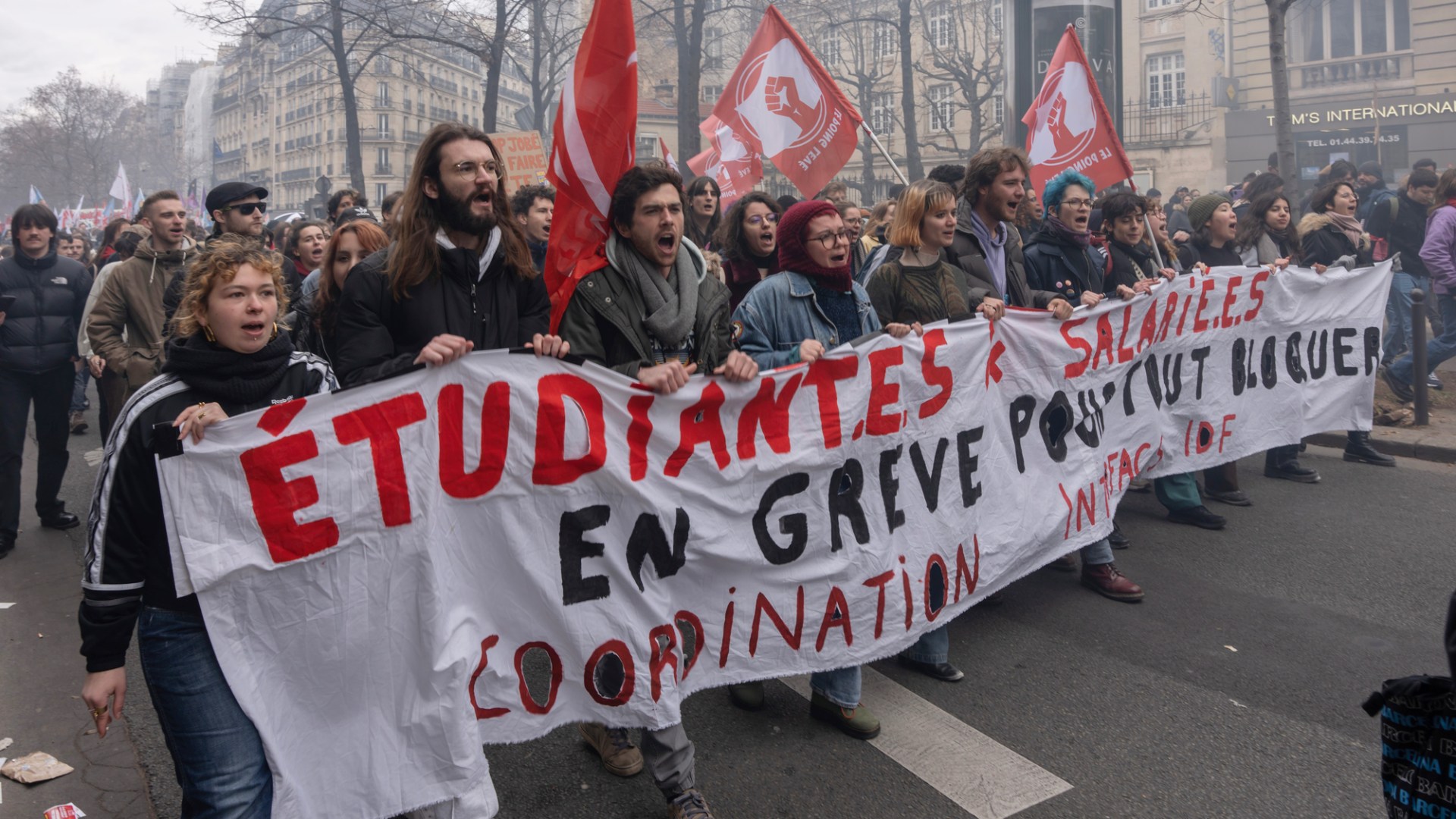Unga människors marscherar och bär en banderoll med röda och svarta bokstäver.
