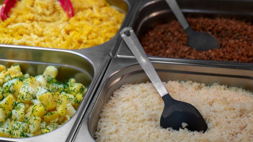 Ris, potatis, makaroner och röd sås i fyra metallbyttor, med slevar i.