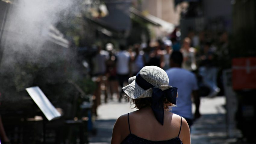 Kvinna i solhatt på gata.