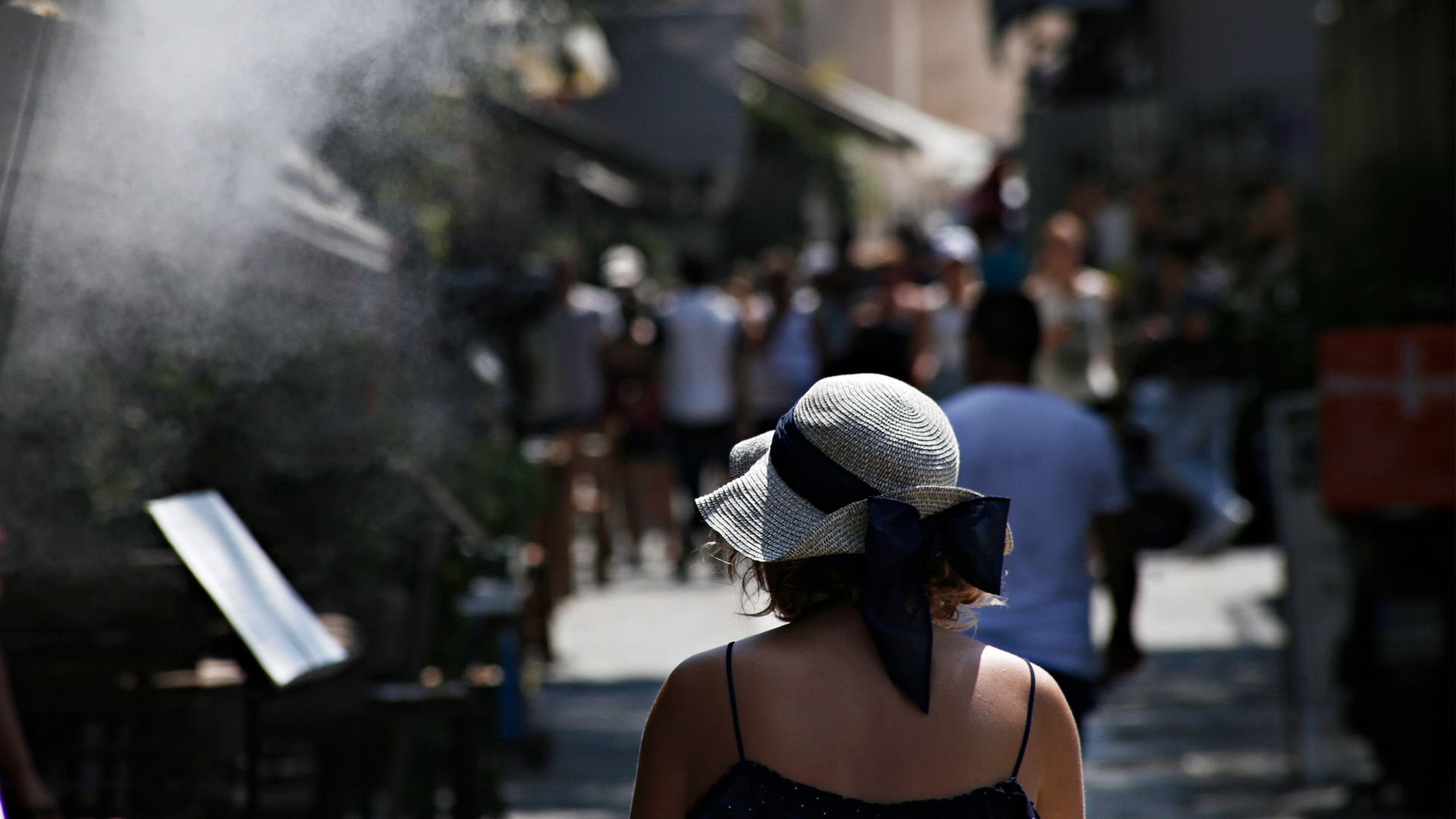 Kvinna i solhatt på gata.