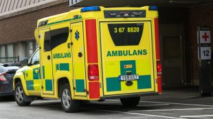 En gul ambulans utanför ett sjukhus.