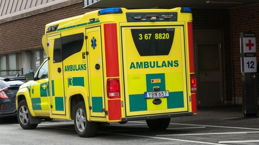 En gul ambulans utanför ett sjukhus.