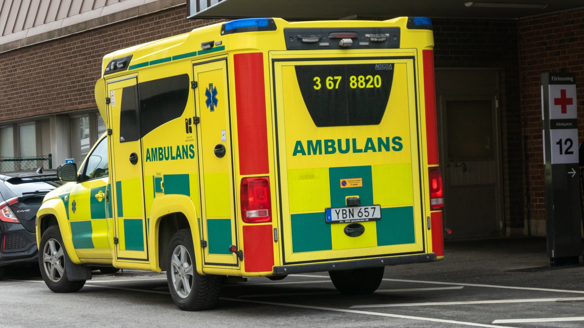 En gul ambulans utanför ett sjukhus.