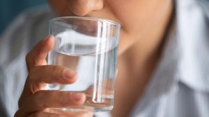 En person dricker ett glas vatten.
