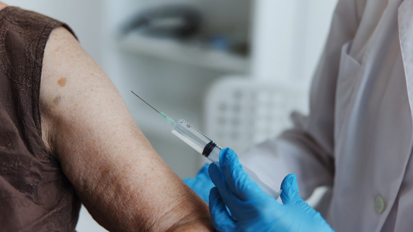 Äldre kvinna får en spruta i överarmen.