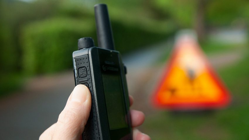 En hand håller i en kommunikationsradio.