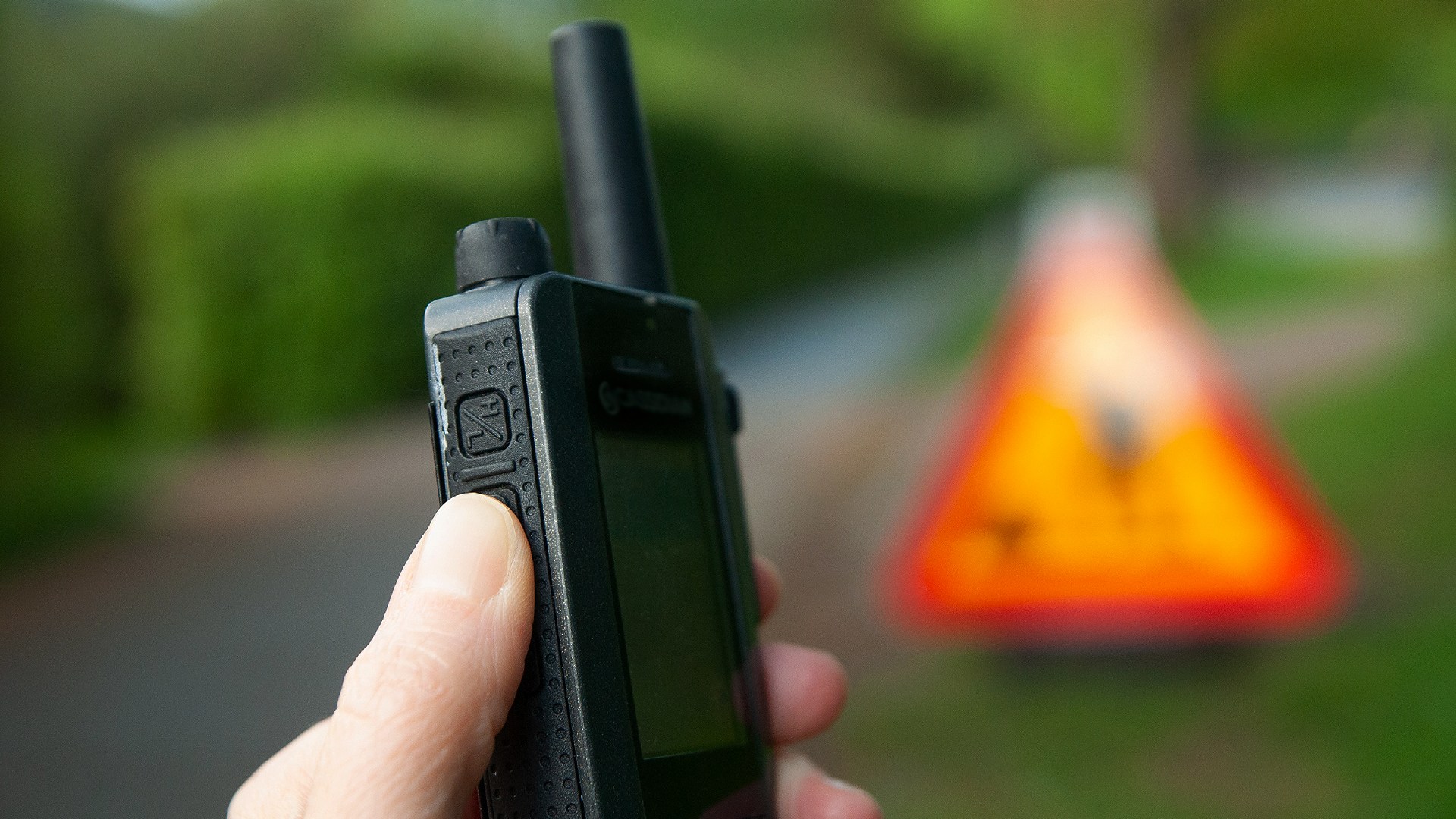 En hand håller i en kommunikationsradio.