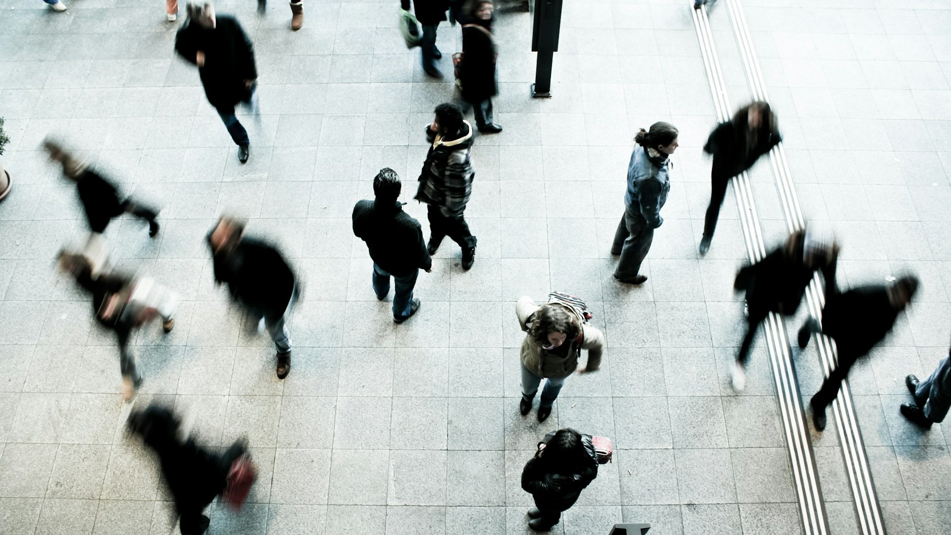 Människor i ytterkläder på stenbelagt golv, ovanifrån.