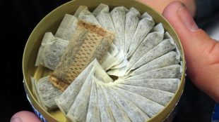 En öppnad snusdosa med portionssnus inuti.