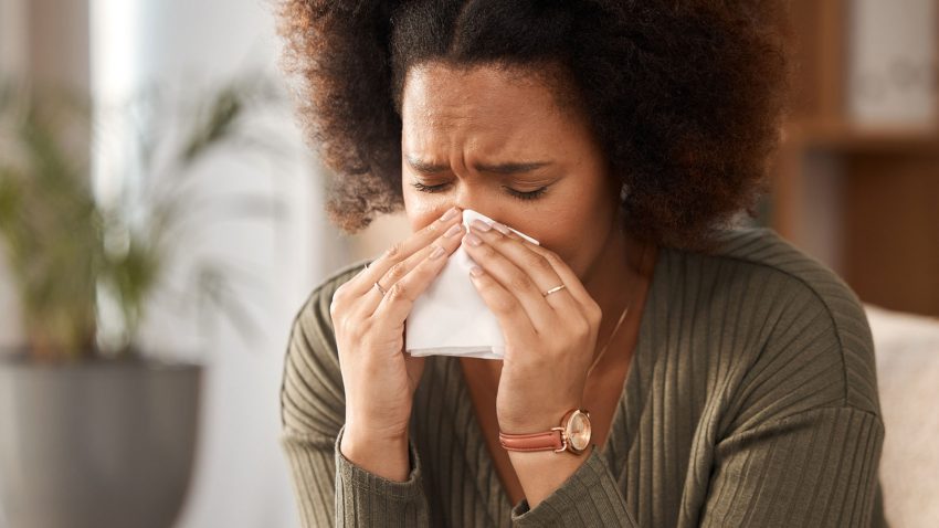 Kvinna snyter sig i näsduk.