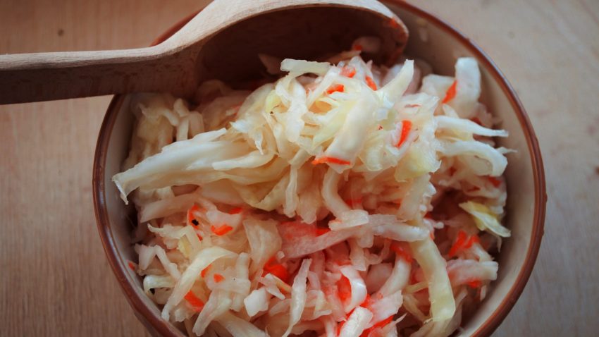 En träskål med riven vitkål och riven morot.