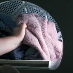 Man håller i en rosa handduk i tvättmaskinen