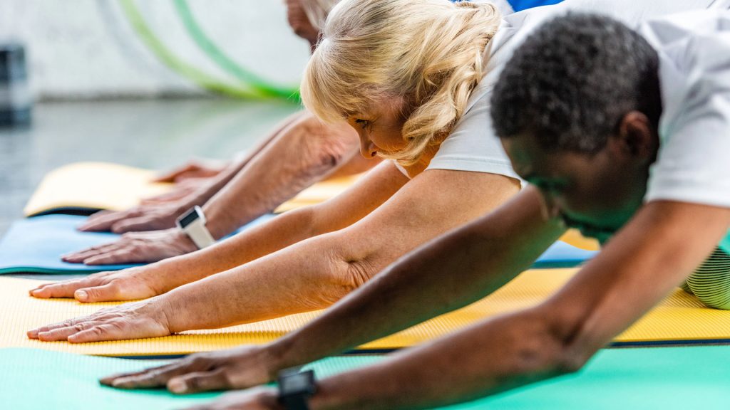 Tre personer stretchar på mattor