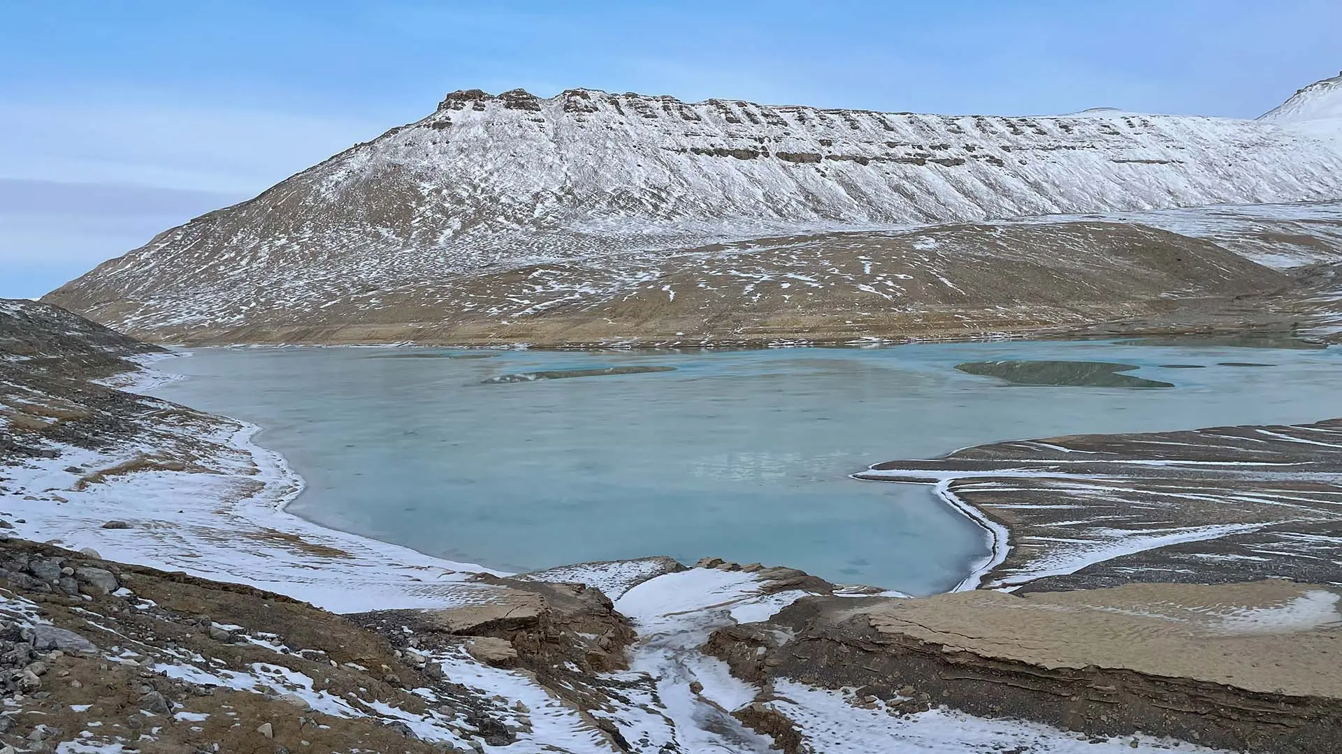 Liten glaciärsjö omgiven av berg.