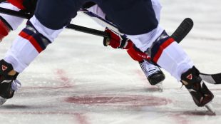 Nedsläpp av puck i match mellan två damlag, varav ett är från Kanada.