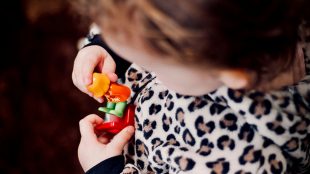 Barn med leksak har en polyestertröja i leopardmönster.