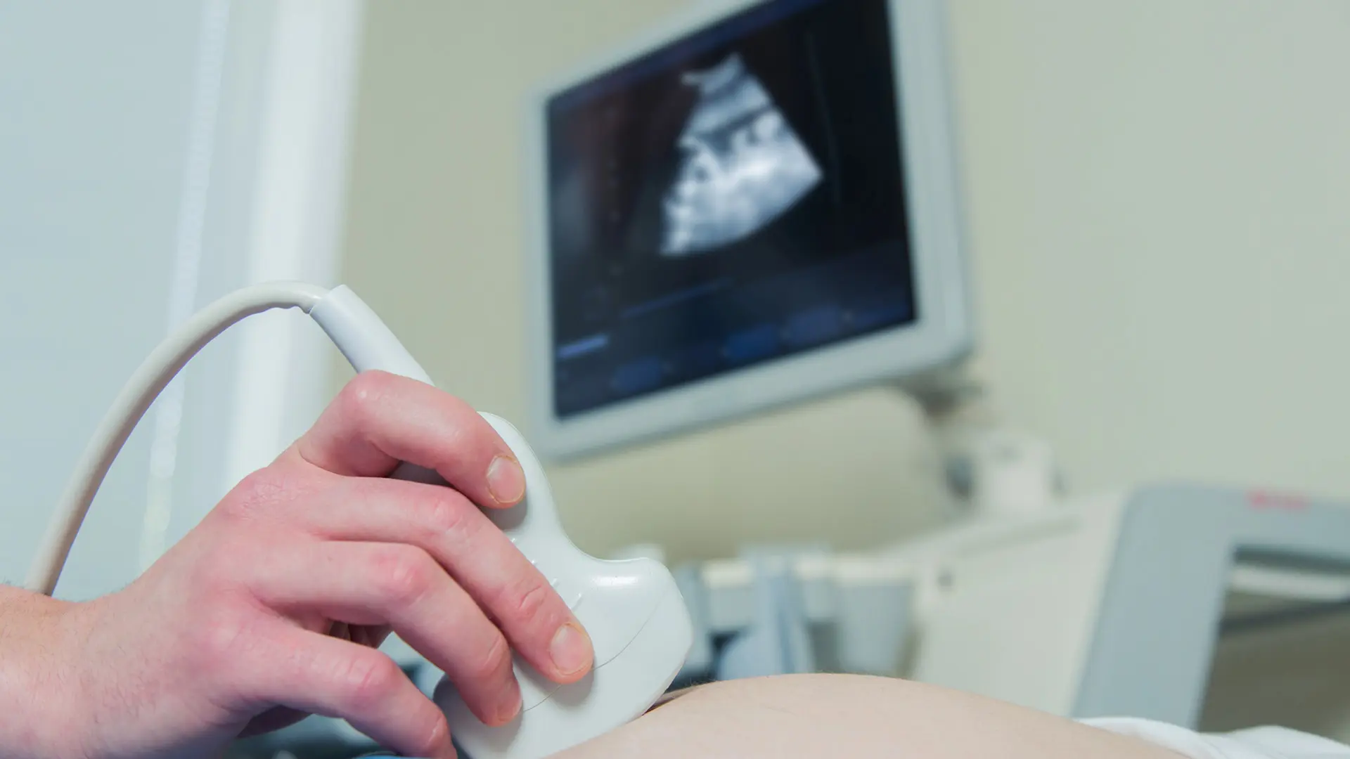 Gravid kvinna gör en ultraljudsundersökning där fostret syns på en skärm.