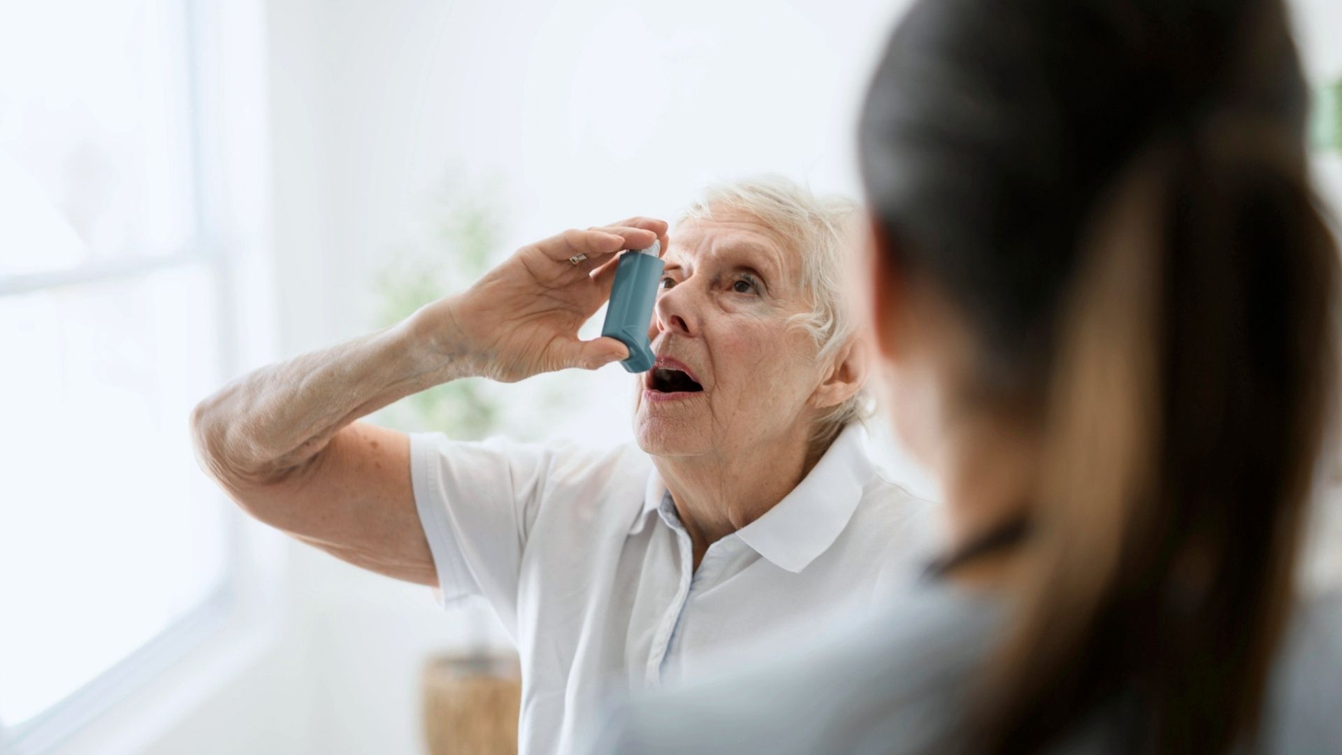 En sjuksköterska hjälper en kvinnlig patient att inhalera med sin inhalator.