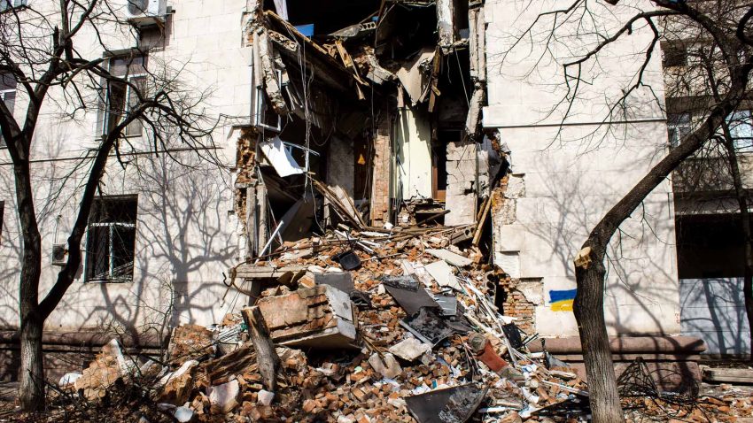Delvis förstörd byggnad Ukraina med bråte utanför.