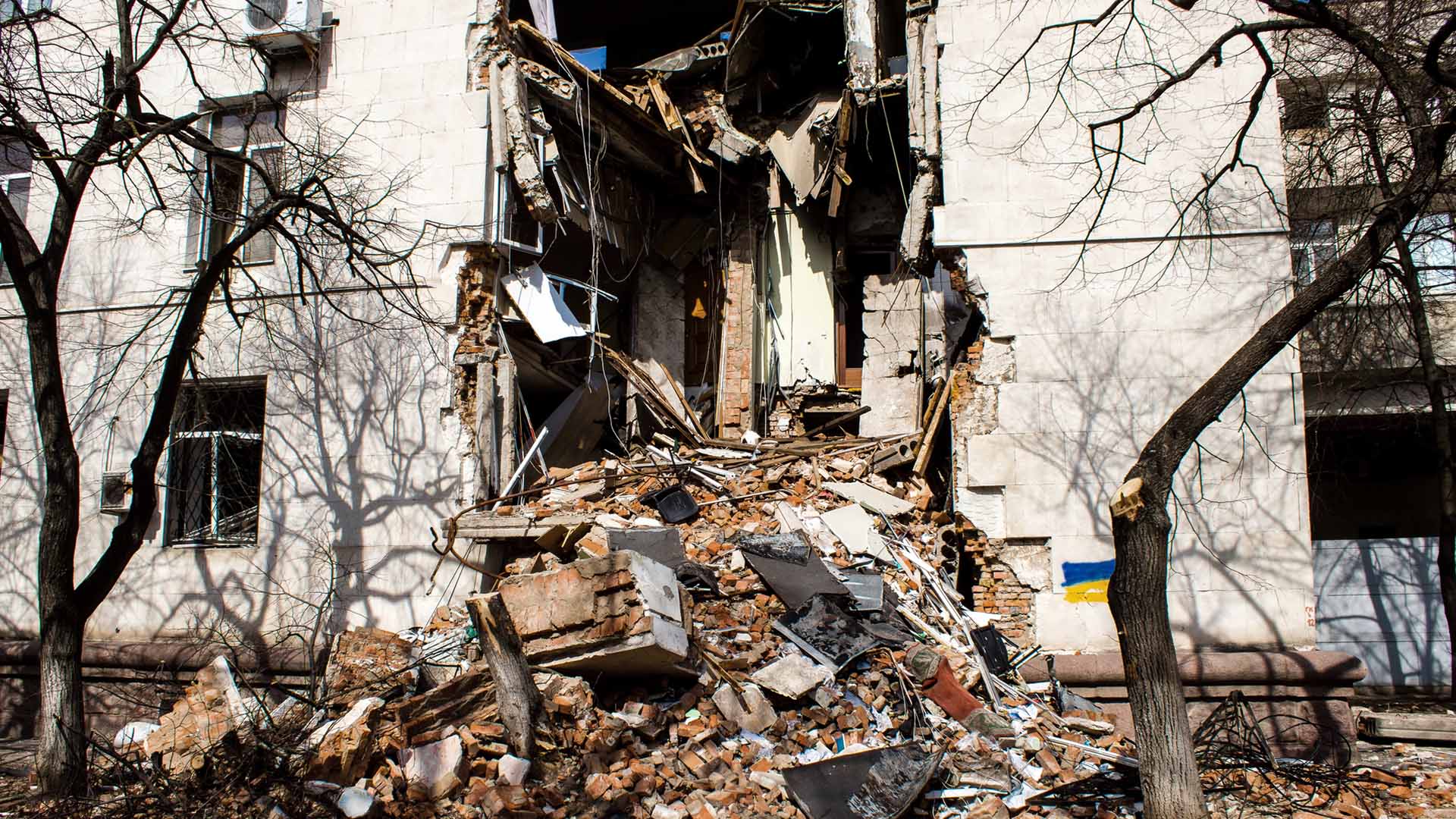 Delvis förstörd byggnad Ukraina med bråte utanför.