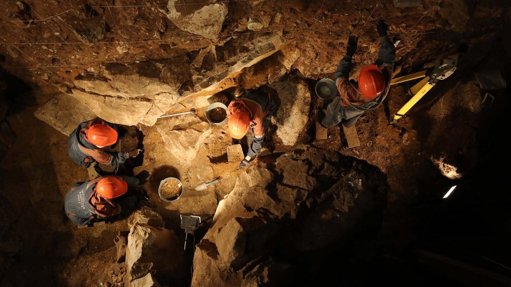 Forskare i röda hjälmar i grotta. 