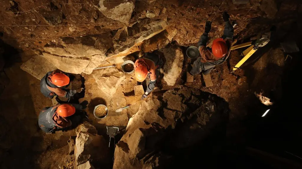 Forskare i röda hjälmar i grotta. 