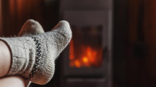 Fötter i ullsockor framför en kamin.