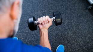 Senior tränar med hantel på gym