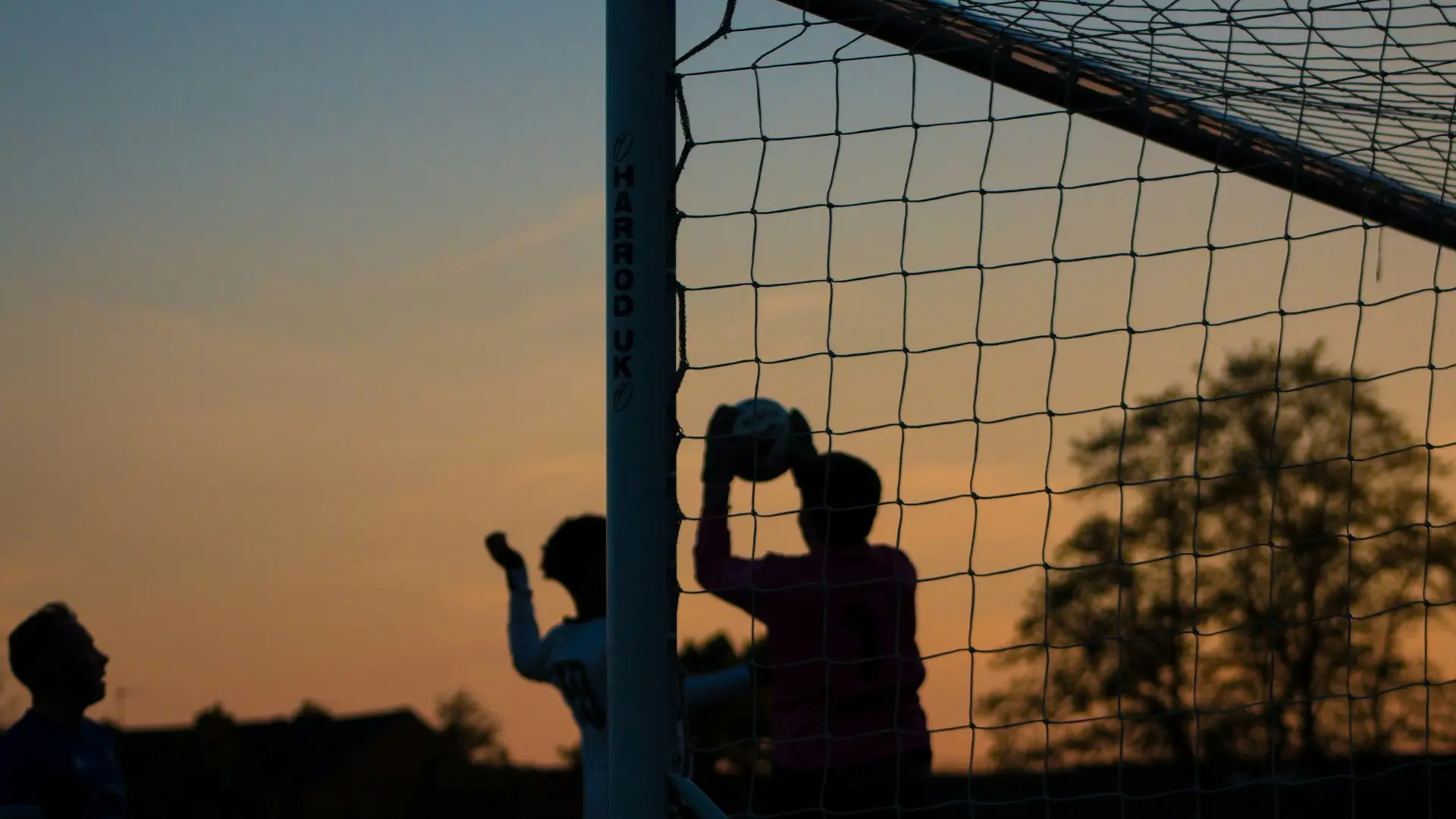 Barn spelar fotboll i skymningen.
