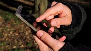 Två händer håller i mobiltelefon.